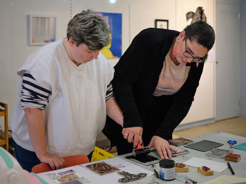 Art teacher assisting autistic student with making art print