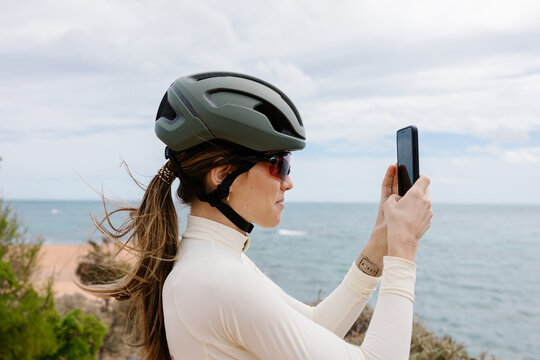 A professional cyclist uses her smartphone to capture a photo