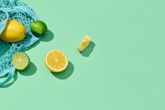 Juicy lime and lemon in mesh bag isolated on a green background