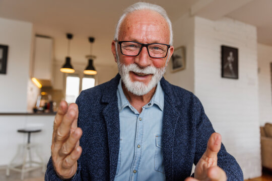 Happy senior businessman gesturing at home