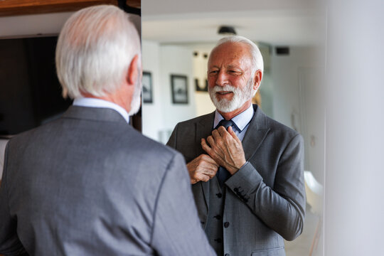 Senior businessman getting dressed in front of mirror
