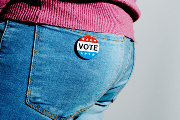 man with a vote badge in the back pocket of his jeans