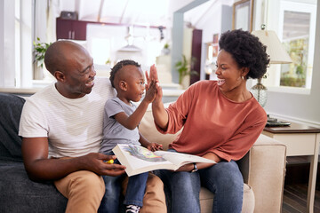 Black family, high five and happy in living room with child, color book and motivation for kid. Lounge, woman and man with smile, together or parents with boy, excited and drawing of youth on couch