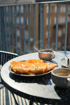 Sandwiches with caviar anf coffee on balcony table in sunlight