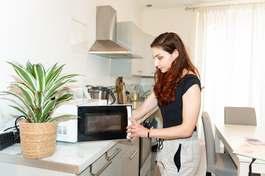 Woman Using The Microwaves At Home.