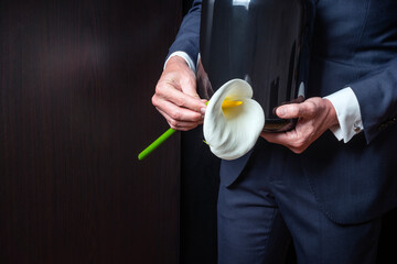 Mourning man in crematorium with cremation urn with ashes and flower at burial or funeral. Copy...