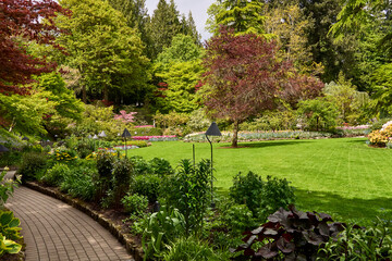 .Pathway through the colorful trees and flower beds in the sunken garden, Butchart Gardens, Victoria