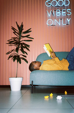 Woman reading notes in notebook lying on sofa