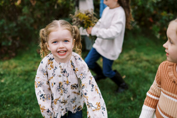 portrait of happy smiling girl with cousins outdoors in autumn