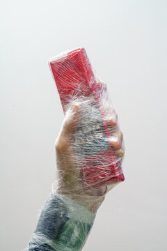 Hand Holding Plastic-Wrapped Red Phone