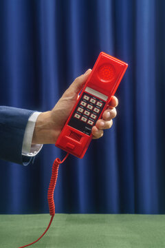 Hand Holding Red Push-Button Telephone