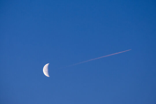 Moon and airplane on morning sky.
