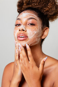 Woman with her hair in a ponytail cleaning her face