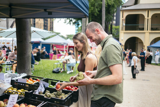 couple buying fruits and vegetables at an outdoor market