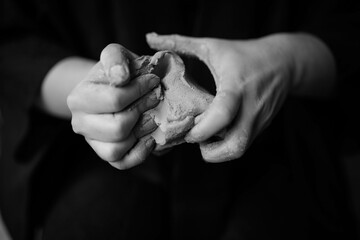 a woman kneads clay in her hands