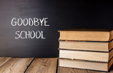 A stack of books with the word Goodbye School written on a chalkboard