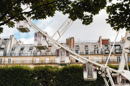 Part of a ferris wheel on the background of a classical Paris house.