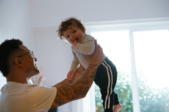 Man lifting child high in an illuminated room
