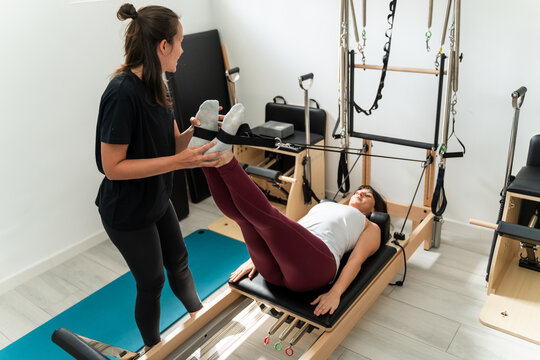 Pilates instructor assisting client on reformer