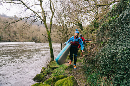 Paddleboarders Trekking by River