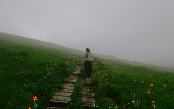 A woman climbing a mountain in bad weather.