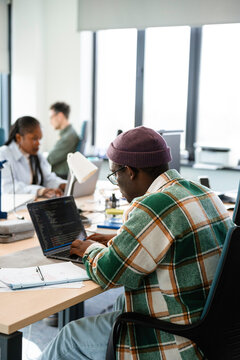 A man is programming on a laptop in the office
