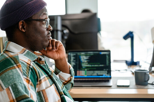 A man is programming on a laptop in the office