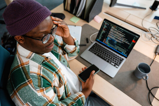 A man is programming on a laptop in the office