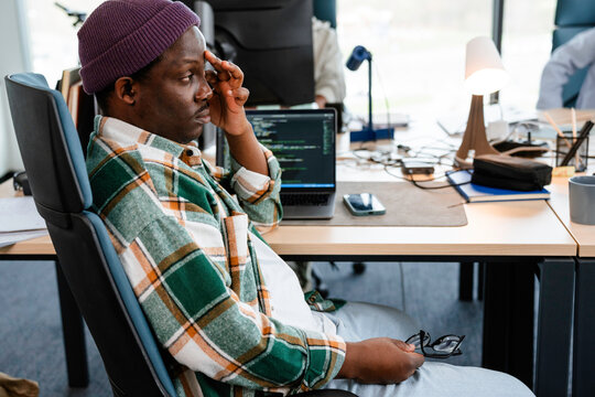 A man is programming on a laptop in the office