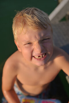 Grinning Boy Shows Off Missing Teeth in a water
