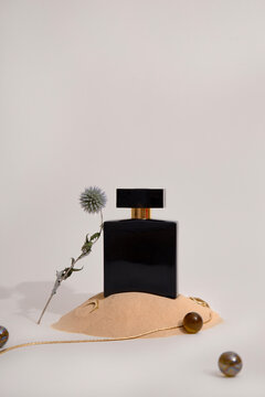 Black perfume bottle styled with sand and dried flower