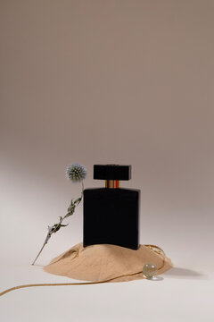 Black perfume bottle styled with sand and dried flower