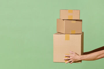 man's hand with cardboard boxes on green background