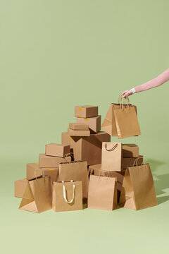 A hand hold paper bag near multiple parcel boxes on green background