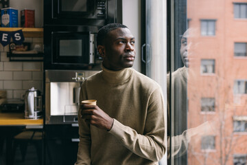 Contemplative man with coffee cup looking out window