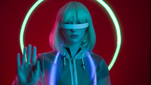 Woman in futuristic costume. Female in modern VR glasses interacting with network while having virtual reality experience. Augmented reality game, future technology.