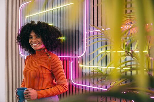 Smiling woman with mug in neon-lit space