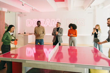 Diverse Team Playing Ping Pong in Creative Office Space