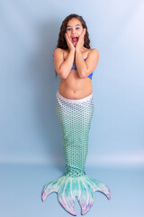 Pretty happy surprised girl in mermaid costume stand on blue background