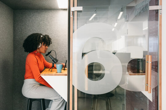 Female podcaster in soundproof recording studio