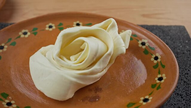 oaxaca cheese or quesillo and a round cheese on a clay plate