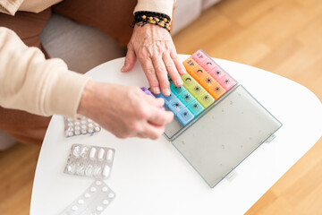 Person organizing pill boxes for the week.
