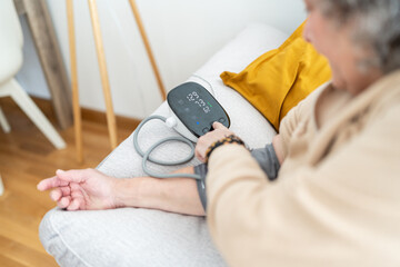 Woman using digital blood pressure monitor.