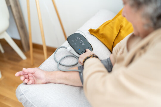 Woman using digital blood pressure monitor.