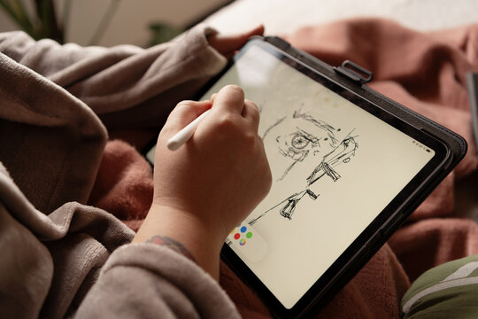 Brunette holds tablet and draws on screen of device. Positive emotions