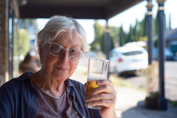 Portrait of older transgender woman sitting outdoors enjoying a beer