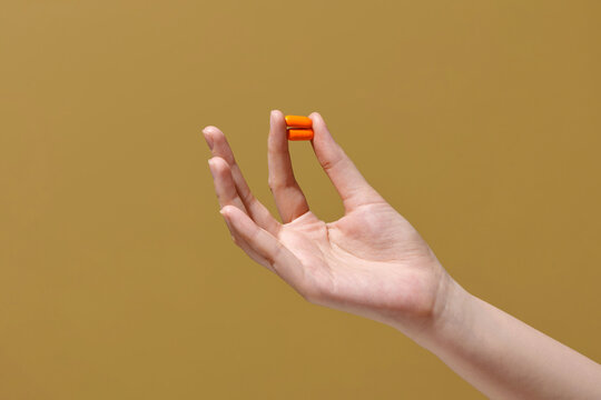 Woman's hand holds two orange capsules