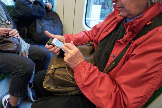 Senior person texting whilst travelling on tram in Melbourne 
