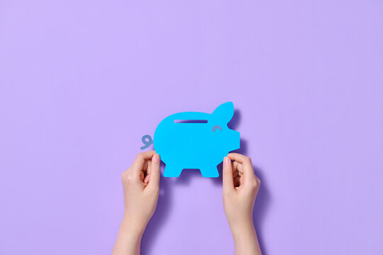 A Piggy bank in human hand on isolated on a purple background