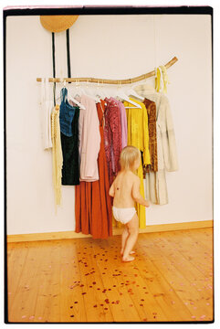 Cute blonde toddler child running back and forth in front of wardrobe